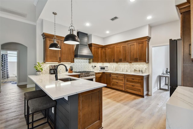 kitchen with visible vents, custom range hood, arched walkways, high end stainless steel range, and a sink