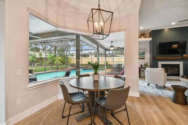 dining room with a glass covered fireplace, baseboards, wood finished floors, and a sunroom