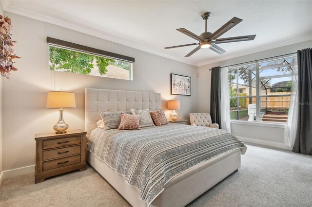 carpeted bedroom featuring baseboards, multiple windows, ornamental molding, and a ceiling fan