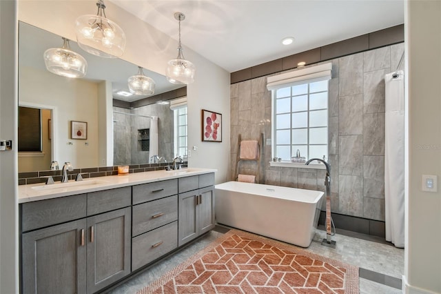 full bathroom featuring double vanity, a stall shower, a freestanding bath, and a sink