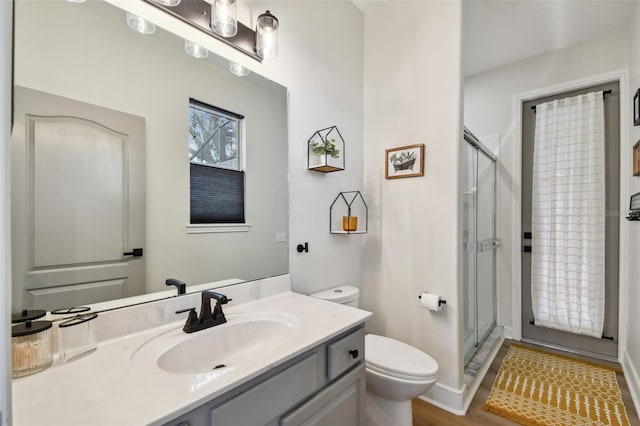 bathroom featuring toilet, a stall shower, and vanity