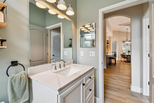 bathroom featuring vanity, a notable chandelier, wood finished floors, and baseboards