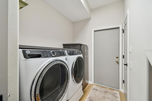 clothes washing area featuring laundry area, washer and dryer, and light wood-style flooring