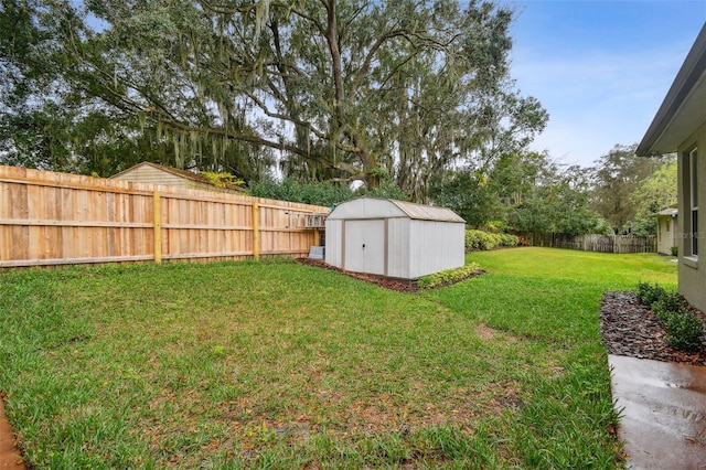 view of yard with an outdoor structure, a fenced backyard, and a shed