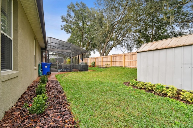 view of yard with a lanai, a storage unit, an outbuilding, and a fenced backyard