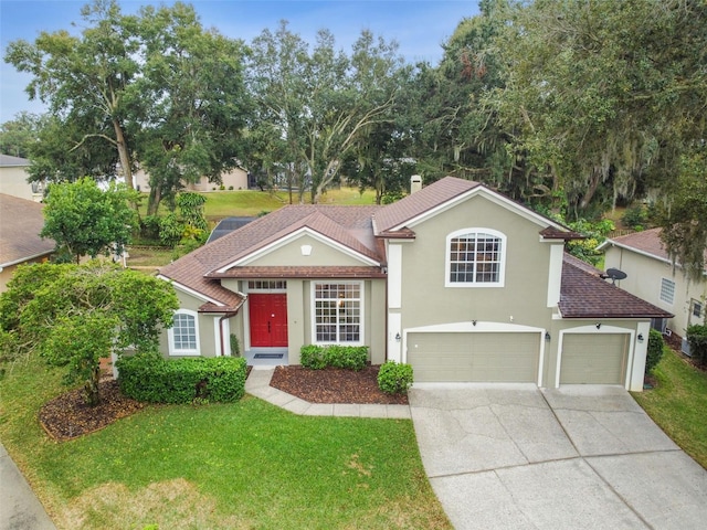 view of front of property with stucco siding, driveway, an attached garage, and a front lawn