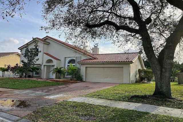 mediterranean / spanish-style house featuring driveway, a tile roof, a front lawn, an attached garage, and a chimney