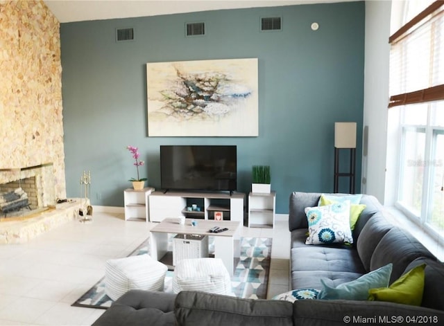 living room with tile patterned floors, visible vents, and a fireplace