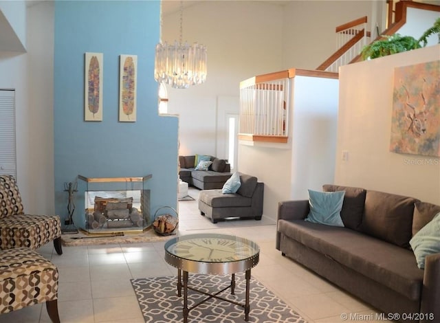 living room featuring tile patterned flooring, a notable chandelier, a high ceiling, and a multi sided fireplace