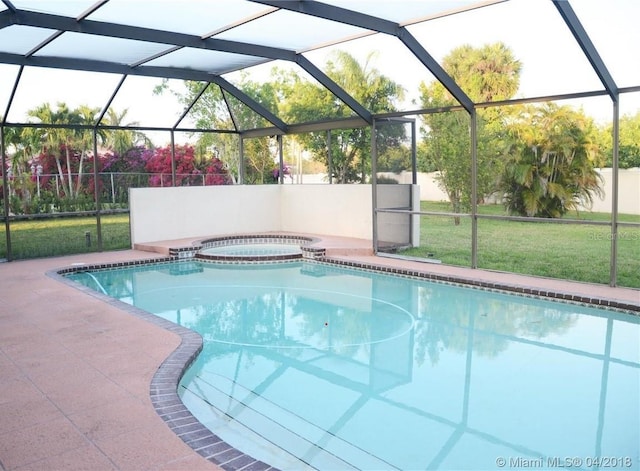 view of swimming pool with a yard, a patio, glass enclosure, and fence