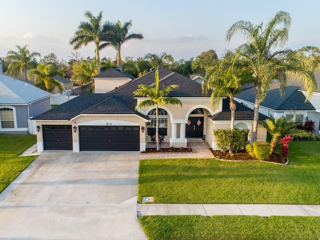 ranch-style house featuring a garage, driveway, a front lawn, and stucco siding