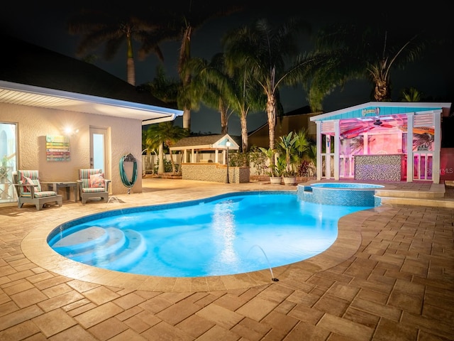 pool at night featuring a gazebo, a patio, and a pool with connected hot tub