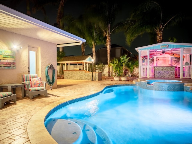 view of swimming pool featuring an outbuilding, a patio area, a pool with connected hot tub, and outdoor dry bar