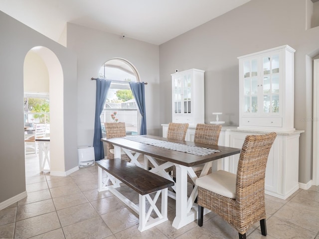 dining room with light tile patterned floors, arched walkways, and baseboards