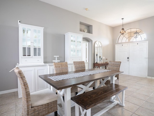 dining room with light tile patterned flooring, arched walkways, and baseboards