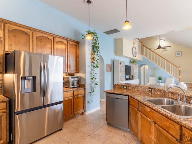 kitchen with visible vents, brown cabinetry, appliances with stainless steel finishes, arched walkways, and a sink