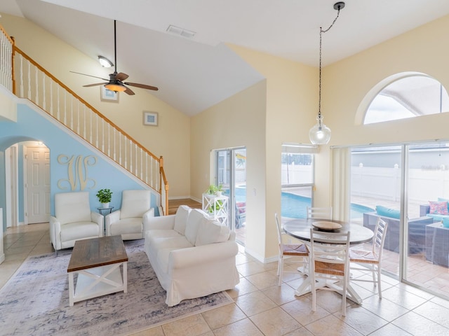 tiled living area with stairs, arched walkways, visible vents, and high vaulted ceiling