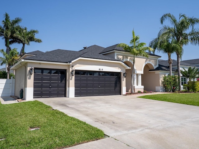 view of front of property with stucco siding, driveway, a front lawn, and a garage