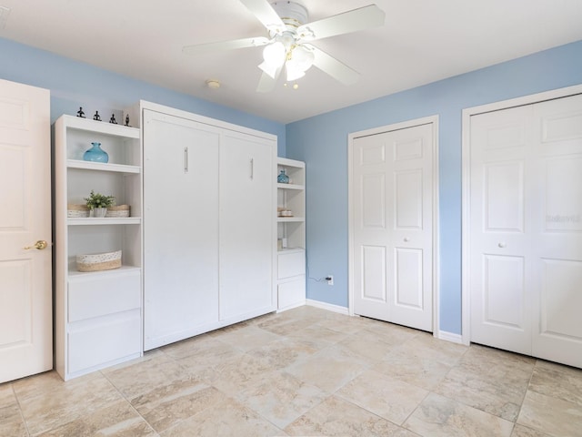 unfurnished bedroom featuring baseboards, two closets, and a ceiling fan