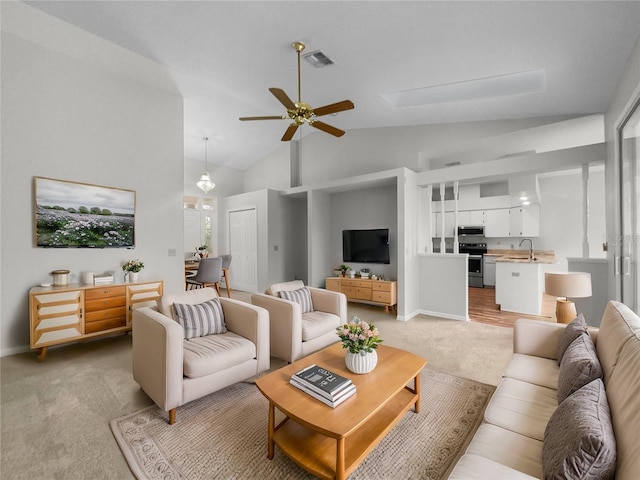 living area with visible vents, high vaulted ceiling, baseboards, light colored carpet, and ceiling fan