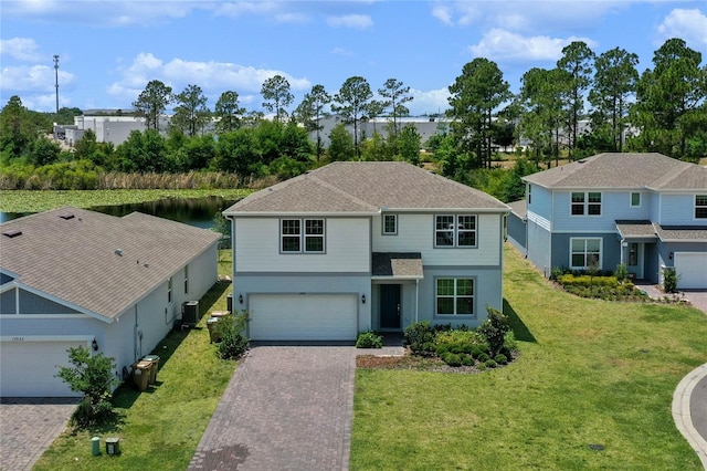 traditional-style home featuring stucco siding, a front lawn, decorative driveway, central AC, and an attached garage