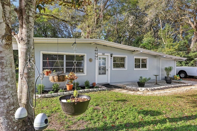 view of front of house with stucco siding and a front lawn