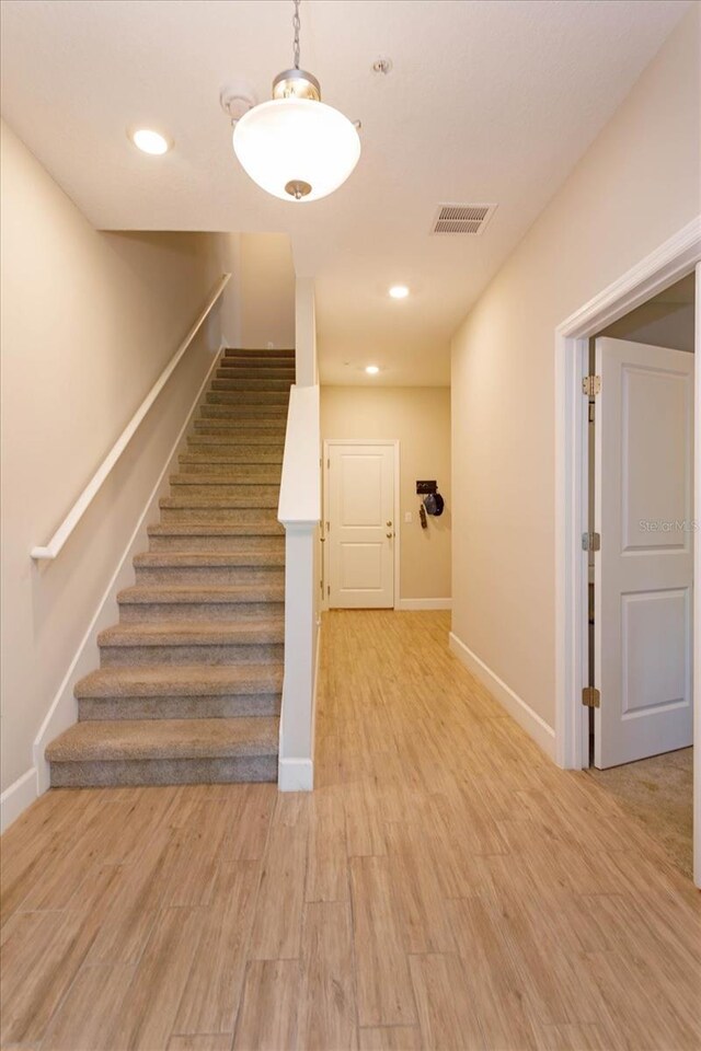 stairway with visible vents, recessed lighting, wood finished floors, and baseboards