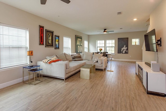 living room featuring visible vents, baseboards, light wood-style floors, and a ceiling fan