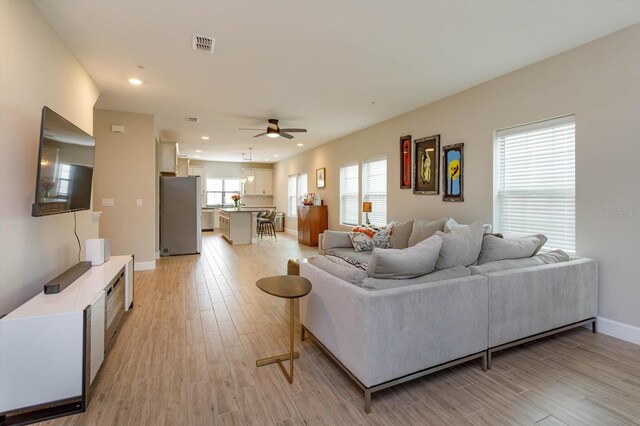 living room featuring light wood-style flooring, recessed lighting, a healthy amount of sunlight, and visible vents