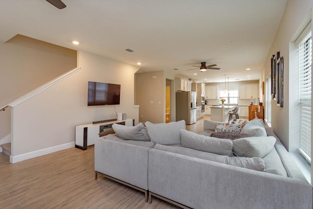 living area with baseboards, ceiling fan, light wood-type flooring, stairs, and recessed lighting