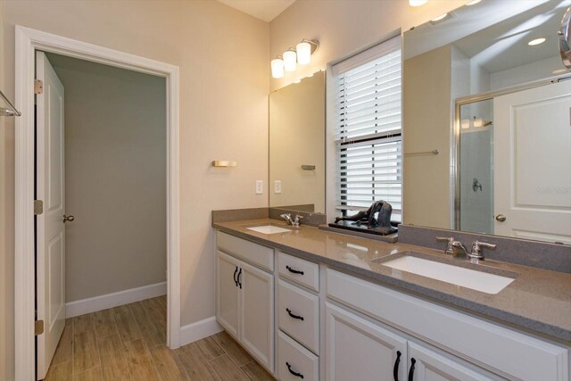 full bathroom featuring a sink, wood finished floors, a stall shower, and double vanity