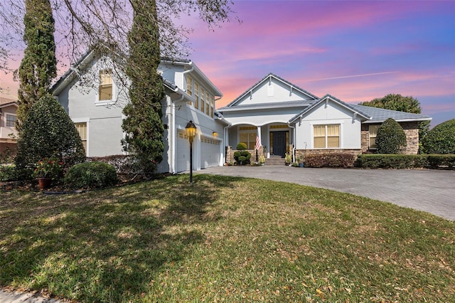 view of front of home featuring stone siding, stucco siding, driveway, and a front lawn