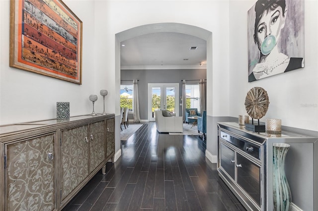 corridor with baseboards, arched walkways, dark wood-style flooring, french doors, and crown molding