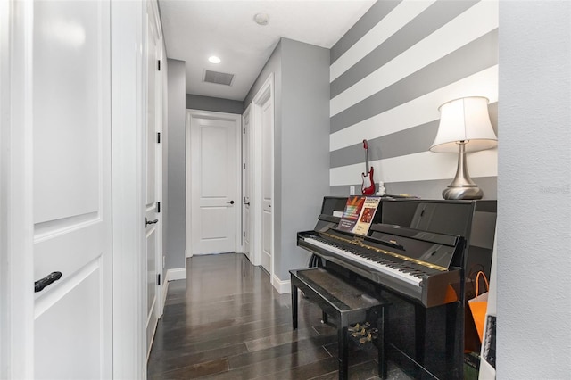 hallway featuring visible vents, baseboards, and wood finished floors