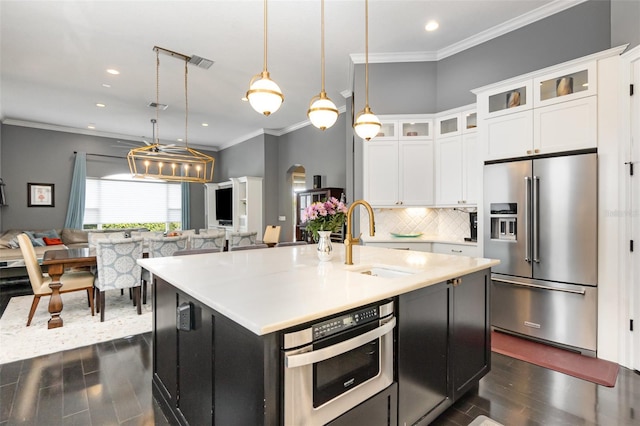 kitchen featuring a sink, backsplash, dark wood-style floors, open floor plan, and stainless steel appliances