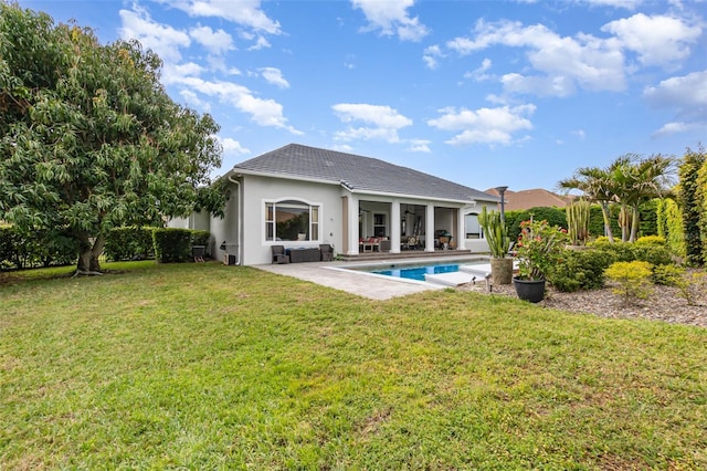 rear view of property with a yard, a patio area, an outdoor pool, and stucco siding