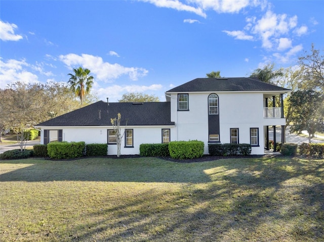 view of front of home with a front lawn, a balcony, and stucco siding