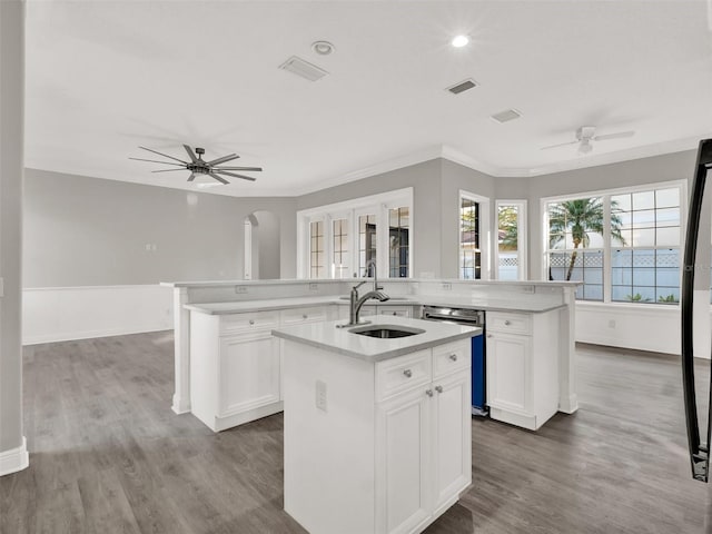 7548 Gathering Dr, Reunion, FL 34747 - kitchen with dishwashing machine, an island with sink, arched walkways, ceiling fan, and a sink