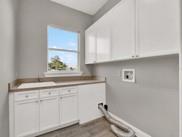 7548 Gathering Dr, Reunion, FL 34747 - washroom with baseboards, washer hookup, wood finished floors, cabinet space, and a sink