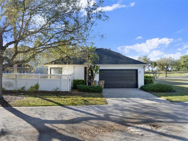 7548 Gathering Dr, Reunion, FL 34747 - ranch-style home featuring roof with shingles, an attached garage, stucco siding, a fenced front yard, and decorative driveway