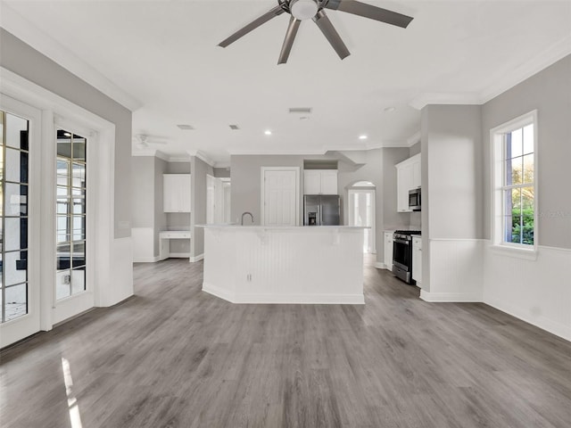 7548 Gathering Dr, Reunion, FL 34747 - unfurnished living room with light wood finished floors, ceiling fan, a wainscoted wall, ornamental molding, and arched walkways