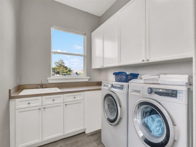 7548 Gathering Dr, Reunion, FL 34747 - laundry area with cabinet space, washer and dryer, wood finished floors, and a sink