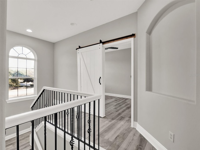 7548 Gathering Dr, Reunion, FL 34747 - hall featuring light wood finished floors, baseboards, a barn door, an upstairs landing, and recessed lighting