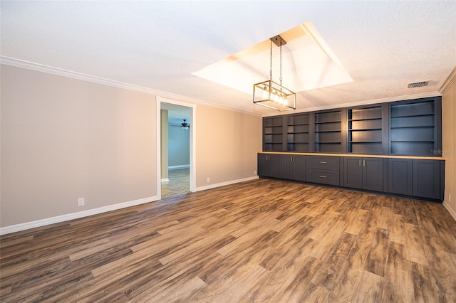 spare room with wood finished floors, baseboards, visible vents, a textured ceiling, and crown molding