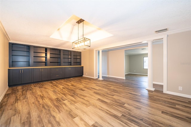 unfurnished room featuring visible vents, ornamental molding, wood finished floors, baseboards, and ornate columns