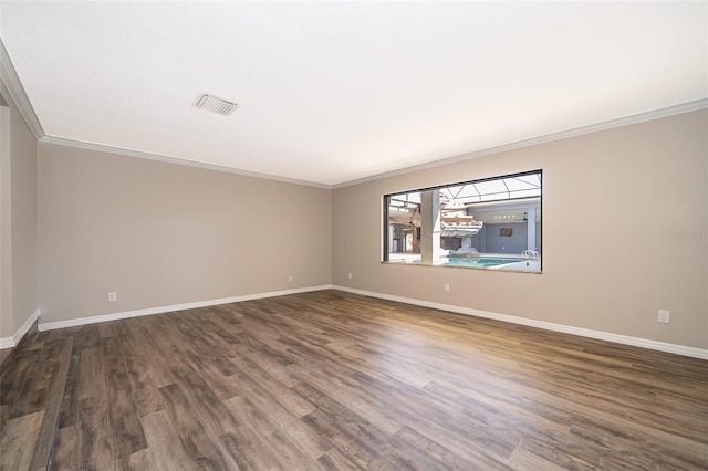 empty room featuring dark wood finished floors, visible vents, baseboards, and ornamental molding