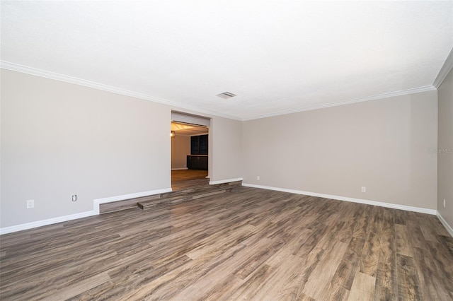 spare room featuring baseboards, wood finished floors, and ornamental molding