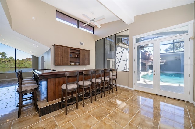 bar with ceiling fan, baseboards, beam ceiling, french doors, and a bar