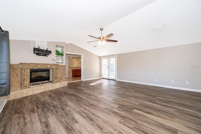 unfurnished living room featuring baseboards, lofted ceiling, a premium fireplace, french doors, and wood finished floors