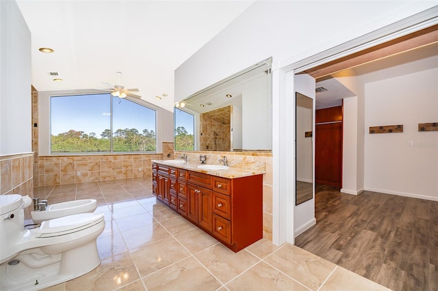 full bathroom featuring vanity, a bidet, a ceiling fan, tile walls, and toilet